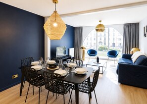 Un espace repas moderne avec une table ronde, des chaises noires et un luminaire suspendu.