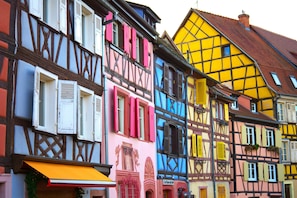 A row of colorful half-timbered buildings with visible shop fronts and awnings. - Outremer – Blue Comfort in the Heart of Colmar (Colmar)