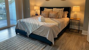 Ein Schlafzimmer mit einem Bett, zwei Nachttischlampen, einer digitalen Uhr und Blick ins Freie.