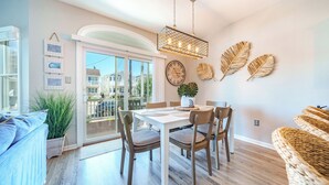 A dining area with a table, chairs, a hanging light fixture, and a view through a glass door. - 2 Blocks to Beach & Boardwalk – 3BR/2BA in Gold Coast, OCNJ (Ocean City)
