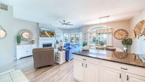 A modern living room with a fireplace, a dining area with a view, and a kitchen with white cabinets. - 2 Blocks to Beach & Boardwalk – 3BR/2BA in Gold Coast, OCNJ (Ocean City)