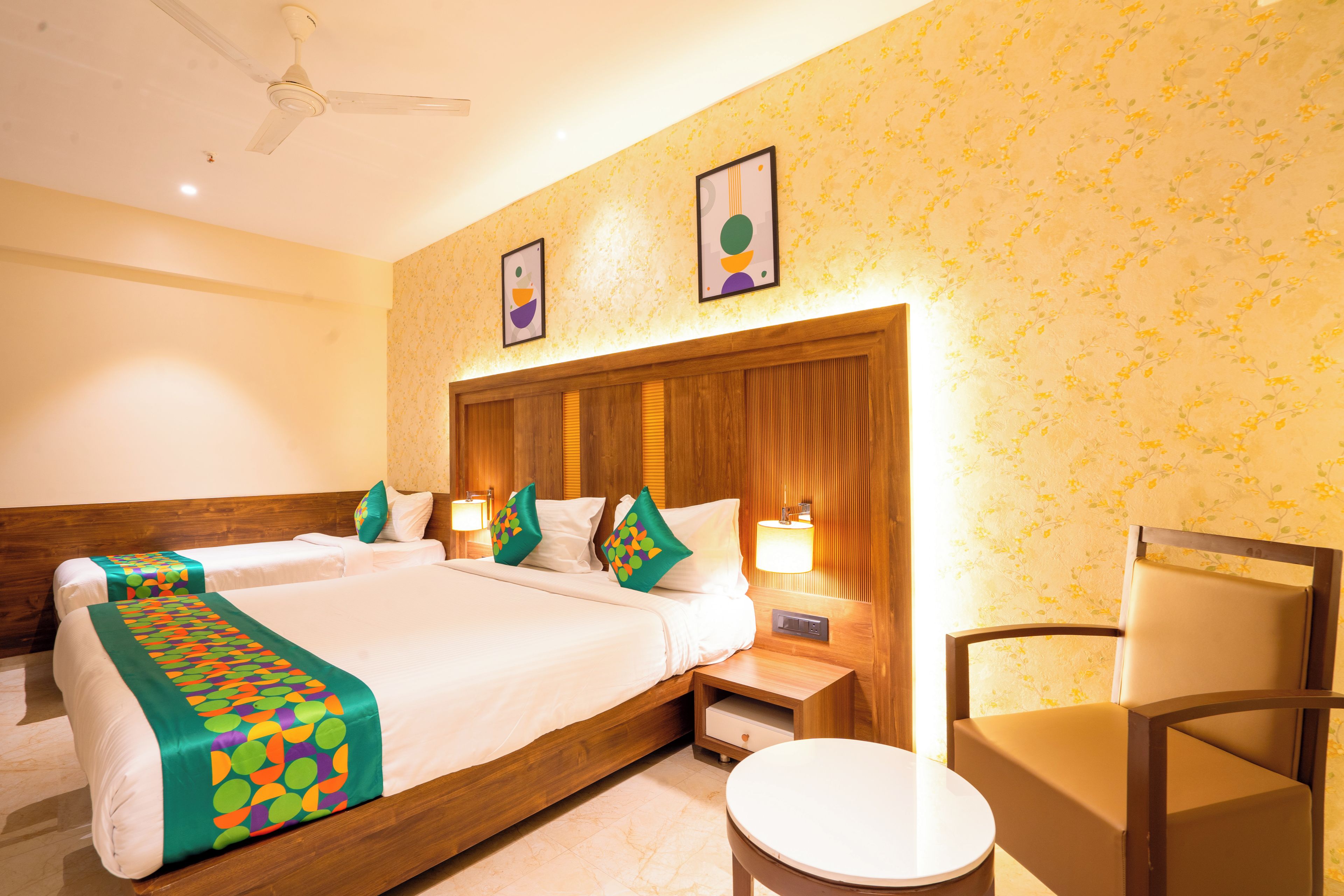 A hotel room with two beds, a wooden headboard, a round table, and a chair.