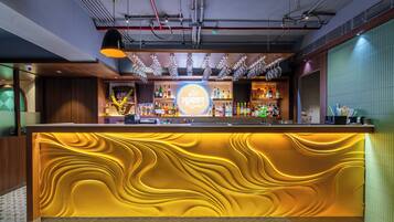 A bar area with a central counter, overhead lighting, and a variety of bottles.