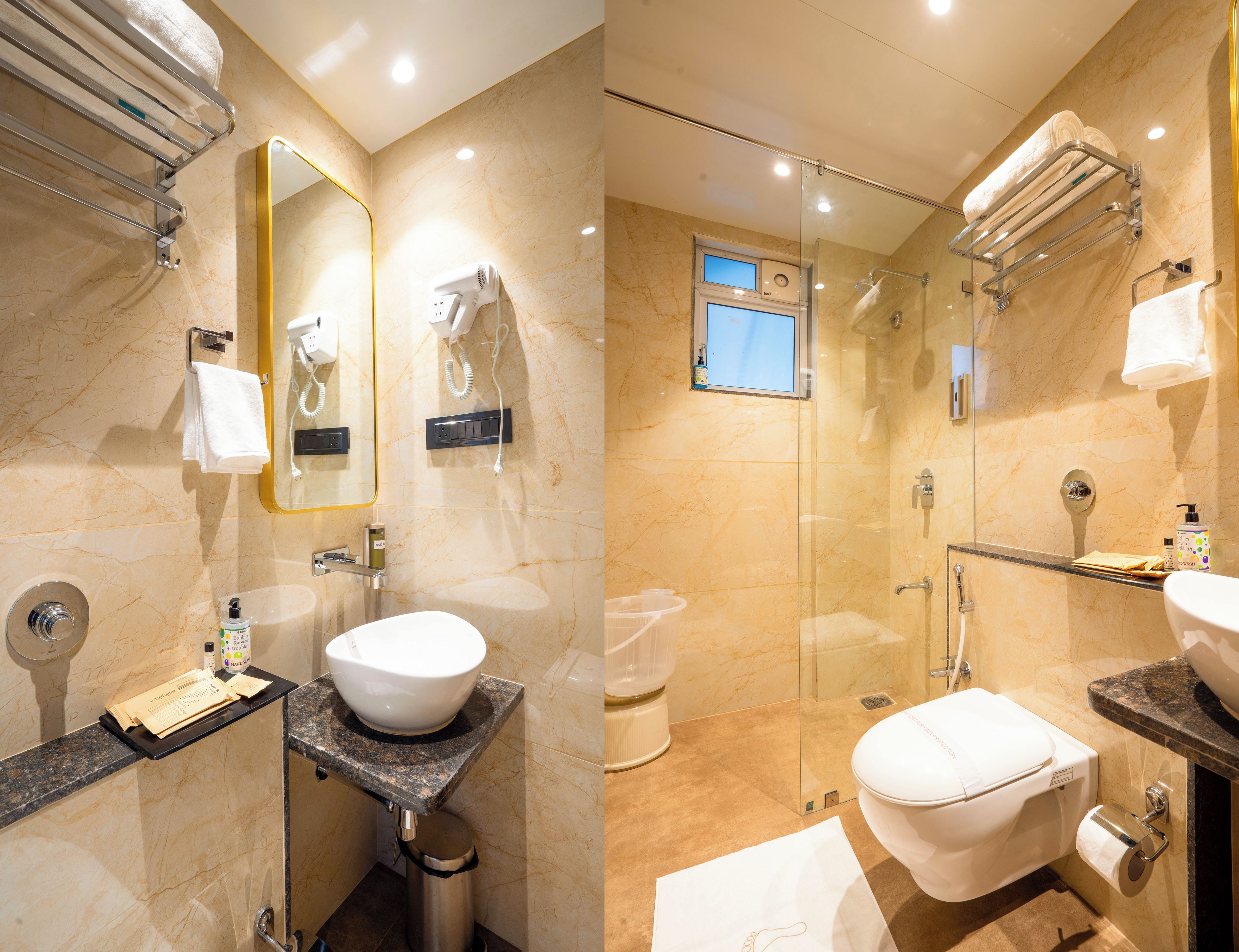 A modern bathroom with a marble sink, a glass-enclosed shower, and a mirror with a gold frame.