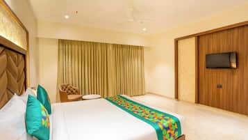 A hotel room with a bed, a chair, a small table, a television, and a curtain.