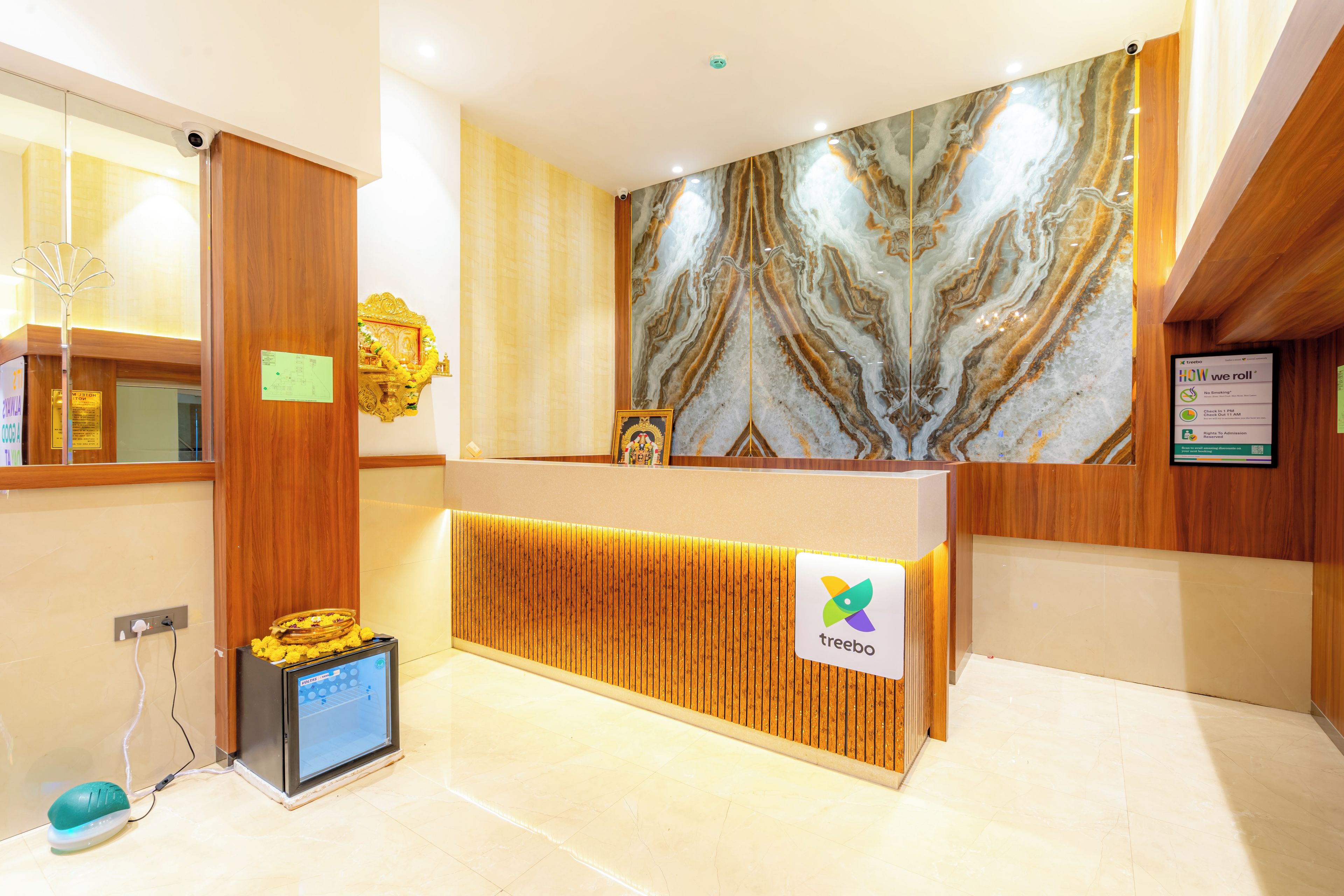 A hotel reception desk with a marble wall, a digital screen, and a sign for the brand 'treebo'.