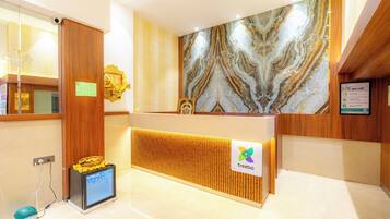 A hotel reception desk with a marble wall, a digital screen, and a sign for the brand 'treebo'.