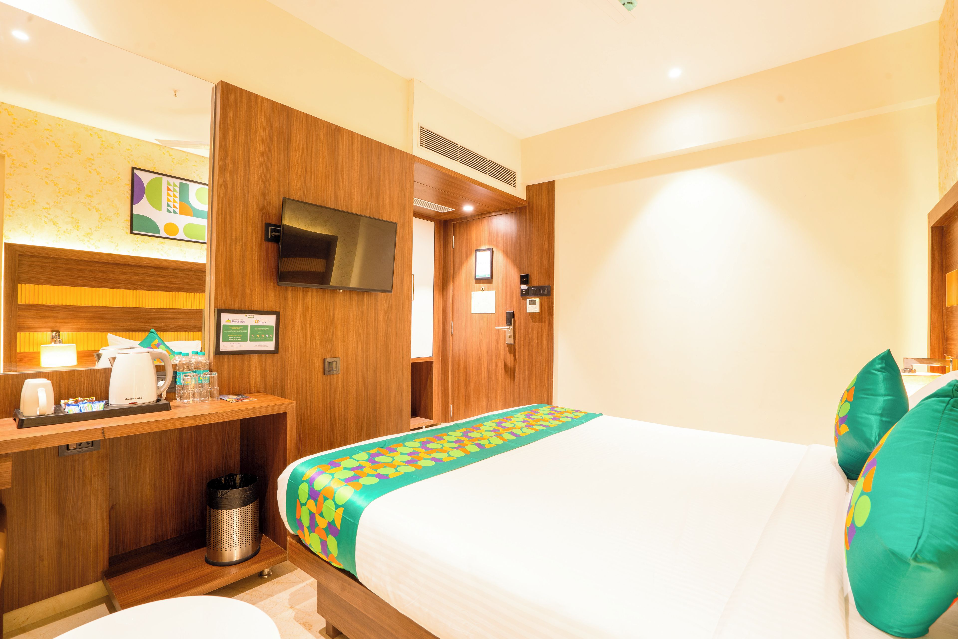 A hotel room with a bed, a desk with a coffee maker, a TV, and a bathroom.