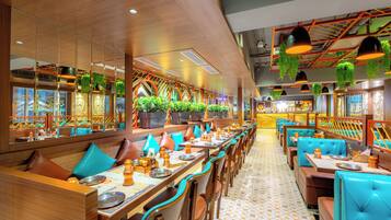 A restaurant with booths and tables, some with blue cushions, and a patterned floor.
