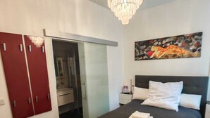 Una camera da letto con un letto, un lampadario, un quadro e un armadio.