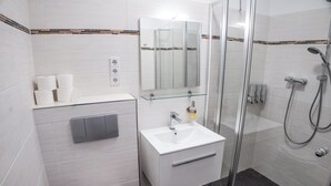 Un bagno moderno con box doccia in vetro, lavandino bianco e specchio sopra, e un water.