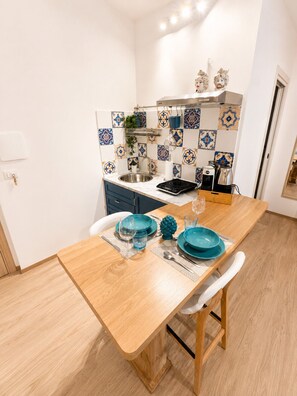 Una cocina moderna con una mesa de madera preparada para dos personas, una cafetera y un lavabo.