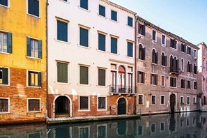 A canal-side building with multiple windows and balconies, reflecting in the water. - Luxury Cannaregio Apartment with Elevator & Private Water Access (Venezia)