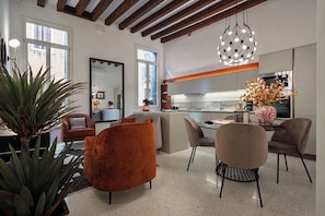 A modern kitchen with a central island, a dining area with chairs, and a large potted plant. - Luxury Cannaregio Apartment with Elevator & Private Water Access (Venezia)