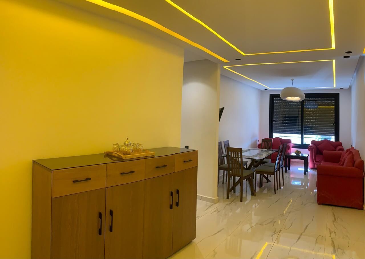 A modern interior with a wooden cabinet, dining table, chairs, and red sofas.