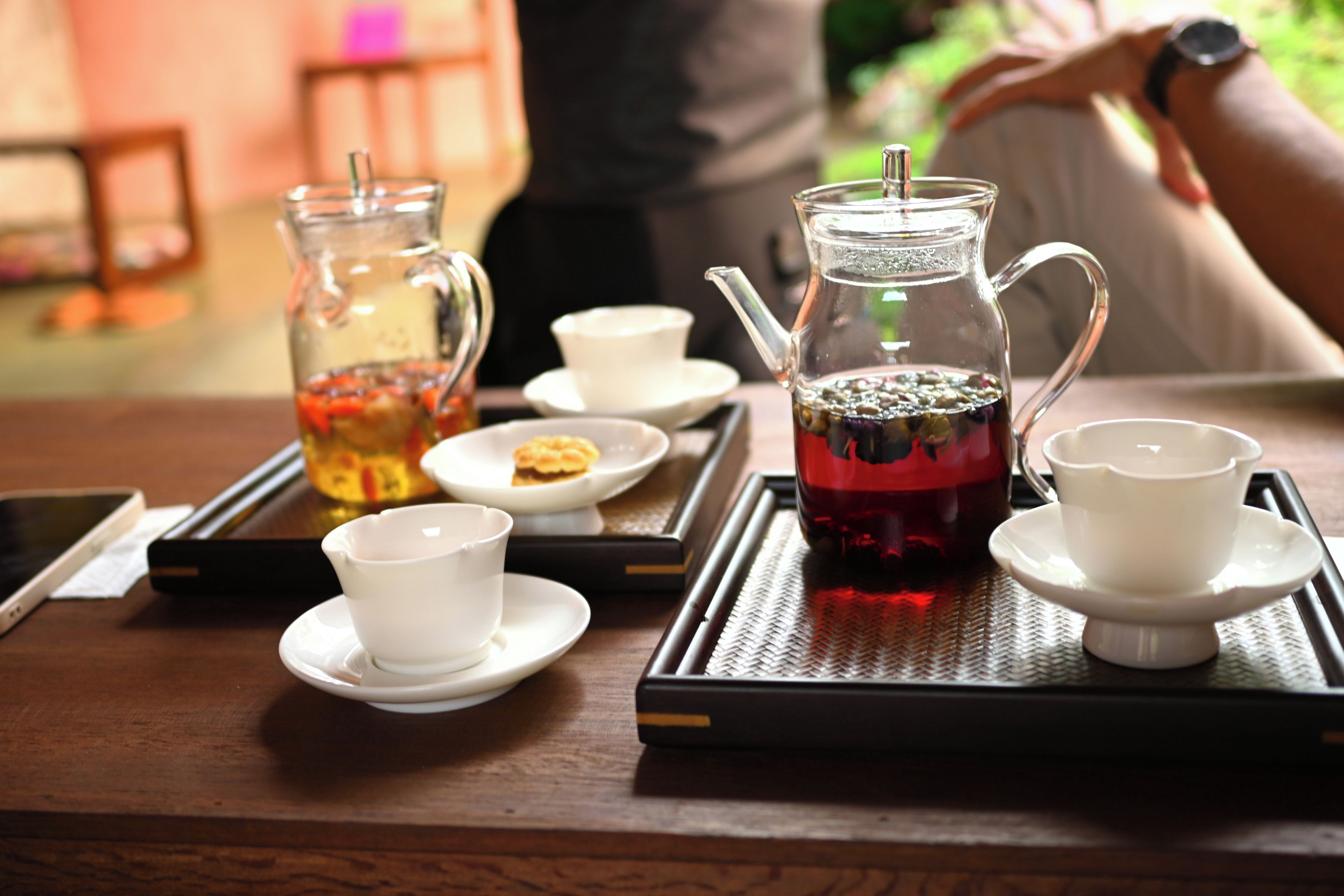 A tray with a glass pitcher and cups, likely containing tea, on a wooden table.