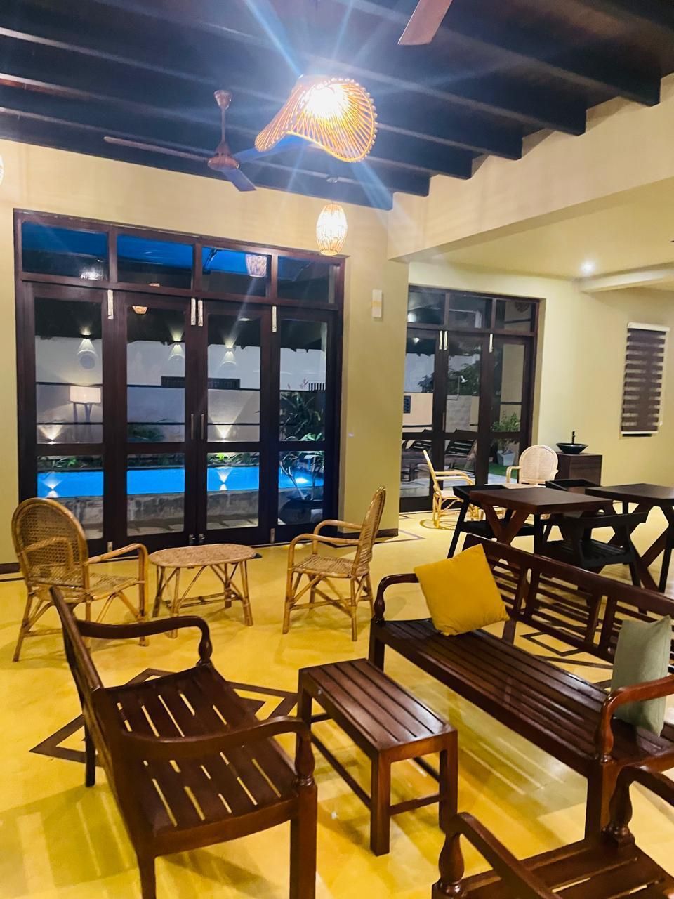 A room with a pool view, wooden furniture, and a ceiling fan.