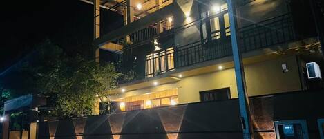 A multi-story building with balconies, a gated entrance, and outdoor lighting.