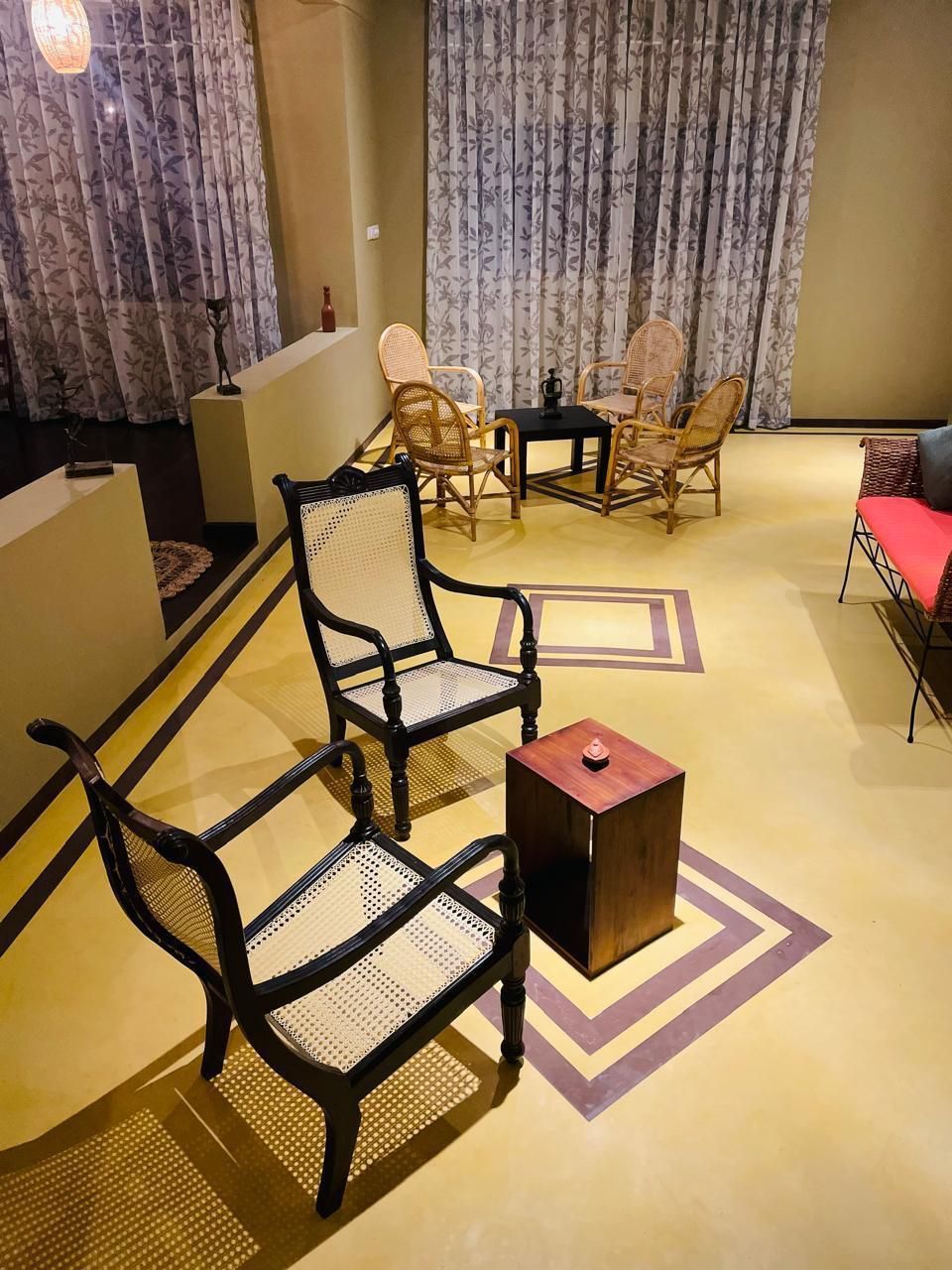A room with a sofa, two armchairs, a small table, and a decorative item on the floor.