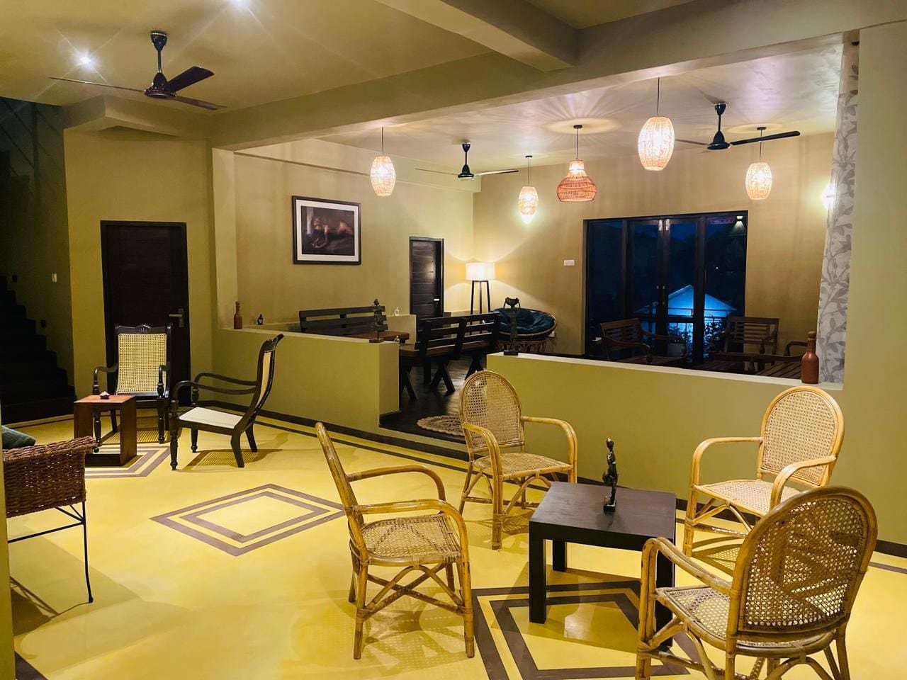 A lobby with wicker furniture, ceiling fans, and pendant lighting.