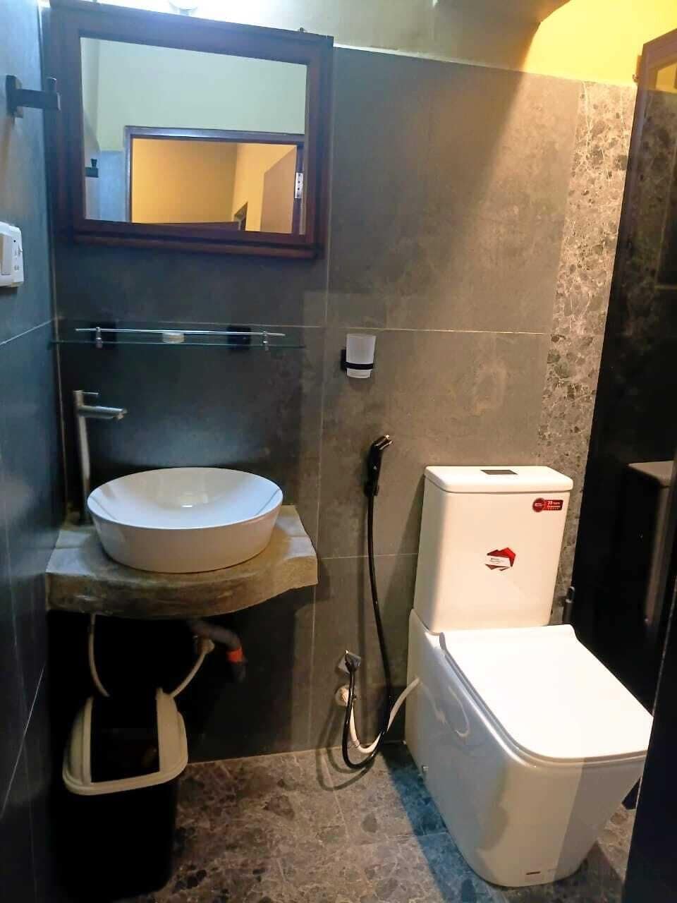 A bathroom with a round sink, a toilet, and a mirror.