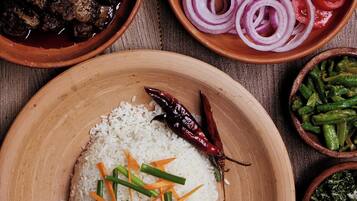 A wooden plate with white rice, green beans, and a red chili pepper.