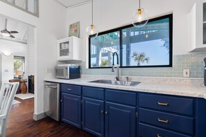 A kitchen with a large window, white cabinets, a microwave, and a dishwasher.