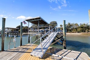A wooden dock with a metal ramp leading to a covered area, a lifeguard chair, and an American flag.