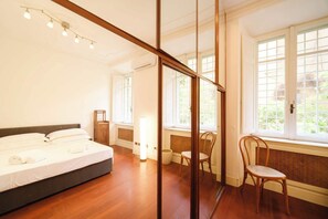 Ein Schlafzimmer mit einem Bett, einem Sessel, einer Heizung und großen Fenstern.