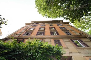 Ein mehrstöckiges Gebäude im klassischen Stil, mit einer symmetrischen Fassade und gleichmäßig angeordneten Fenstern und Fensterläden.