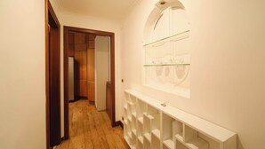 Een gang met houten vloeren, een witte console tafel en een glazen displaykast aan de muur.