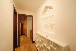 Ein Flur mit Holzboden, einem weißen Konsolentisch und einer Glasvitrine an der Wand.