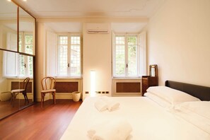 A hotel room with a large bed, two windows, a mirror, a chair, and a bedside table. - BuddyRent - Oasi with Private Pool - Trastevere - 6 (Roma)