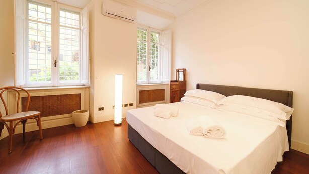 Een hotelkamer met een bed, een stoel, een raam en een wandairconditioner.