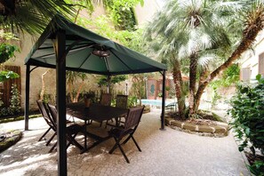 Eine Terrassengruppe im Freien mit Tisch und Stühlen, umgeben von Palmen und Pflanzen.