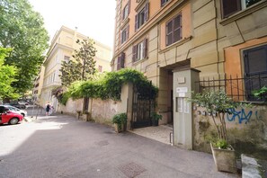 A narrow street with buildings, a red car, and a person walking. - BuddyRent - Oasi with Private Pool - Trastevere - 6 (Roma)