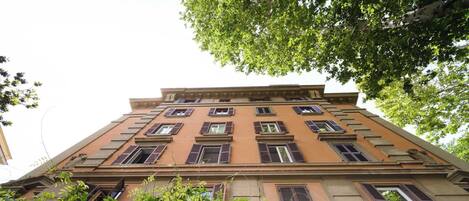 A multi-story building with a classic architectural style, featuring a symmetrical facade with evenly spaced windows and shutters.