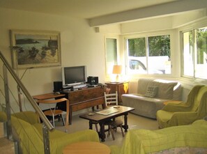 A living room with a sofa, a table, a television, and a painting on the wall.