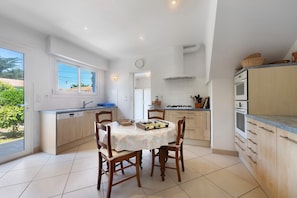 A modern kitchen with a dining table, chairs, and a window.
