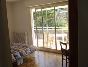 A bedroom with a bed, a radiator, a window, and a view of the outdoors.