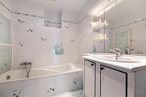 A bathroom with a bathtub, two sinks, and a mirror.