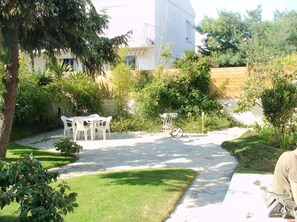 A garden with a table and chairs, a bicycle, and a building in the background.