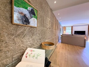 Uma sala de estar moderna com uma parede de pedra, um quadro com ovelhas, uma tigela de madeira e um sofá.