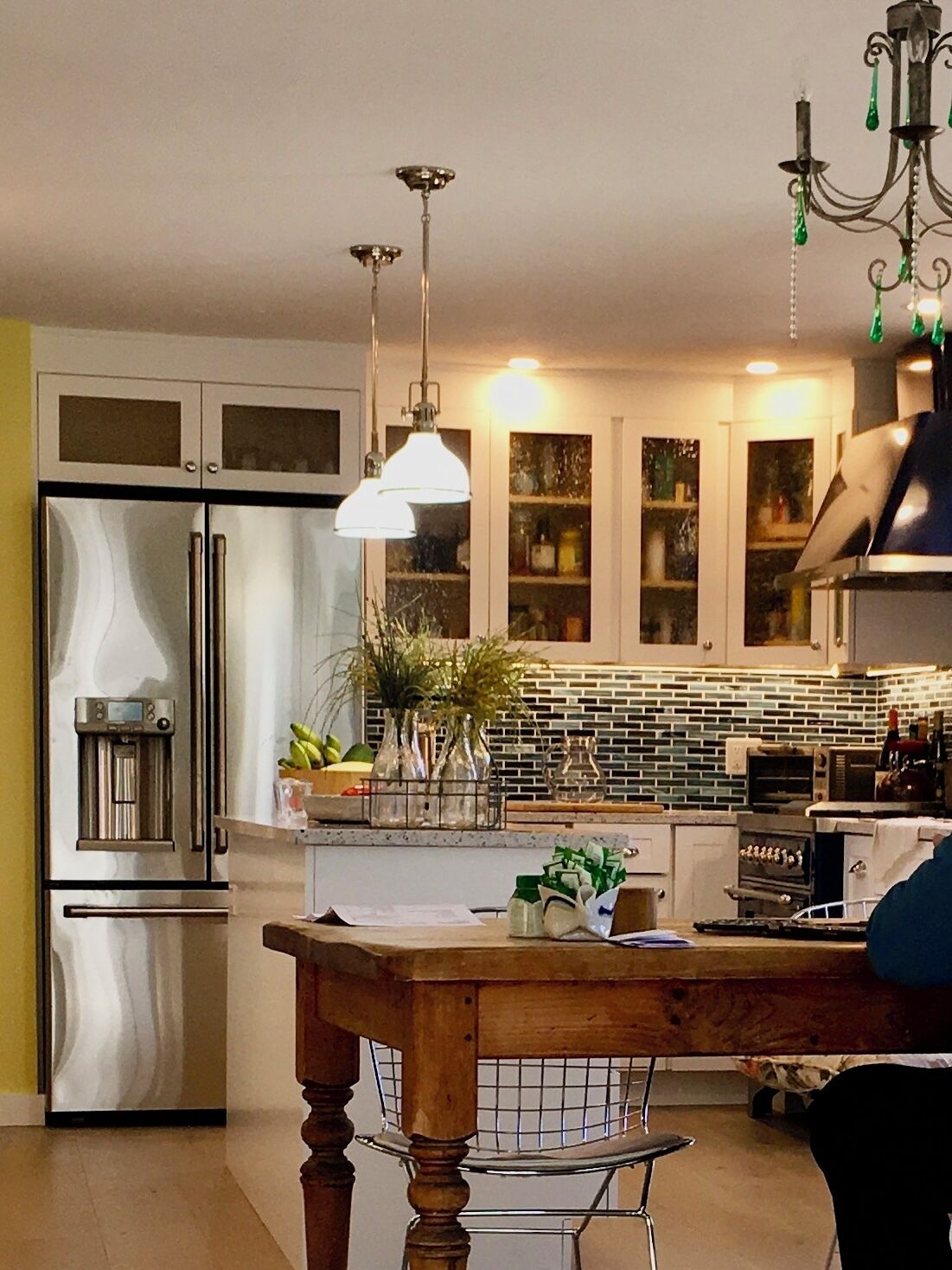 A modern kitchen with stainless steel appliances, a wooden dining table, and pendant lighting.