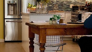 Eine moderne Küche mit Edelstahlgeräten, einem Holztisch und Pendelleuchten.