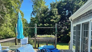 Eine Holzterrasse mit Gartenmöbeln, einer Pergola und Blick auf einen Garten.