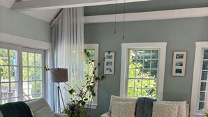 Ein Wohnzimmer mit zwei Sofas, einem Couchtisch, einer Topfpflanze und einem Fenster mit Blick auf Grünflächen.