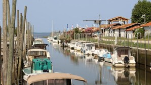 A marina with boats docked along the water, wooden posts, and buildings with red roofs.