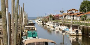 Un port de plaisance oĂč des bateaux sont amarrĂ©s le long de lâeau, avec des poteaux en bois et des bĂątiments aux toits rouges.
