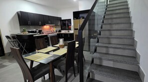 A compact kitchen with dark cabinets, a gas stove, and a dining area with a table and chairs. - Sunflower Villa Punta Cana (Punta Cana)